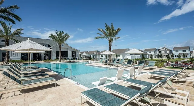 a view of a house with pool lawn chairs under an umbrella