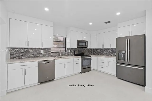 a kitchen with granite countertop white cabinets and stainless steel appliances