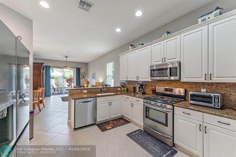 a large white kitchen with stainless steel appliances granite countertop a stove and a sink