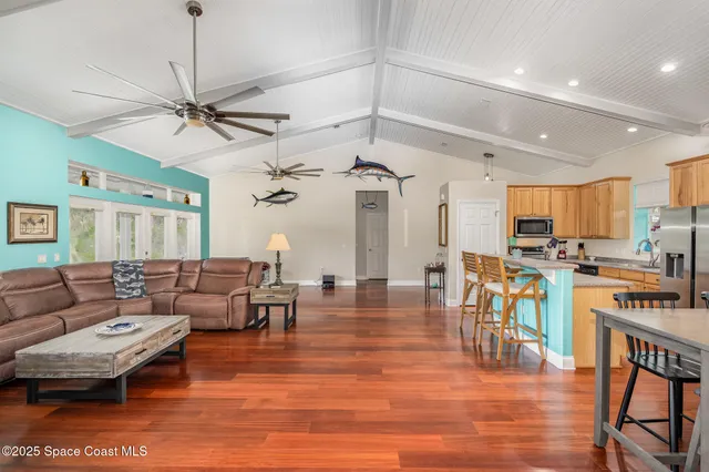 a living room with furniture kitchen view and a wooden floor