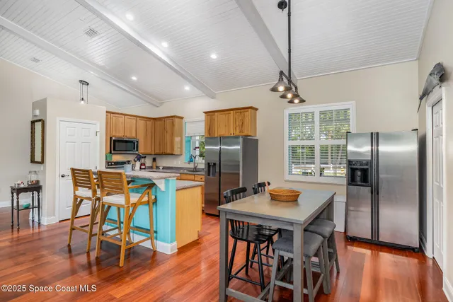 a kitchen with stainless steel appliances kitchen island granite countertop a dining table chairs refrigerator and sink
