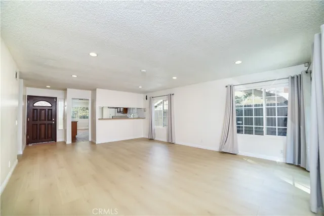 a view of an empty room with a window and kitchen area