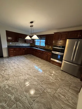 a kitchen with granite countertop a refrigerator and a stove top oven