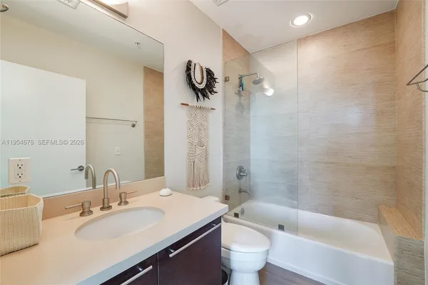 a bathroom with a bathtub shower sink vanity mirror and toilet