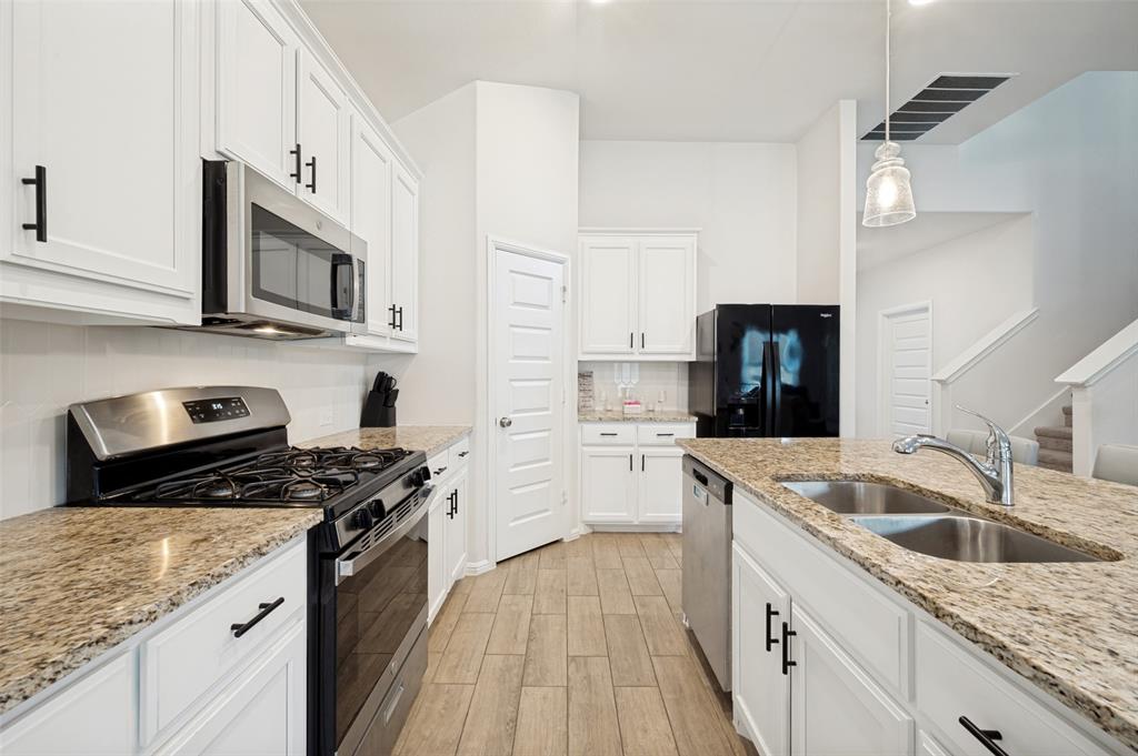 14065 Ilderton Street Pilot Point, TX 76258 - Photo 7 of 19 14065 Ilsderton St., Pilot Point Tx Modern kitchen featuring white cabinetry, stainless steel appliances, a dual basin sink, wood-finish flooring, and light-colored countertops