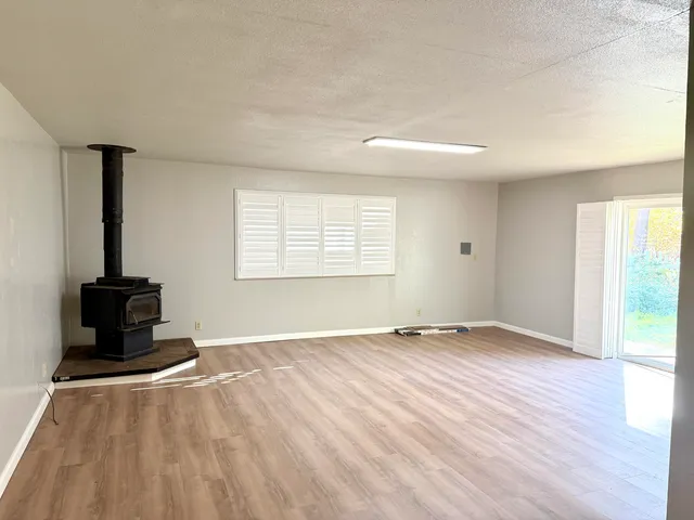 a view of an empty room with wooden floor and windows