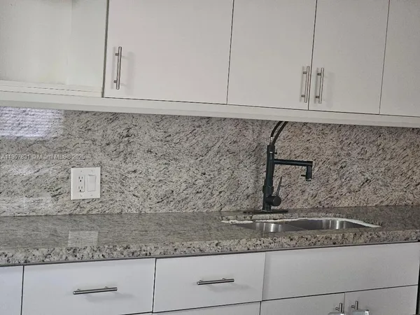 a kitchen with granite countertop white cabinets and a white stainless steel appliances