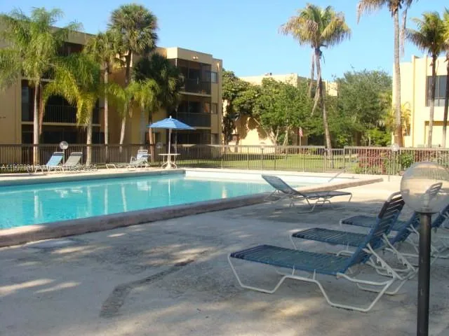a view of a swimming pool with a lawn chairs under palm trees