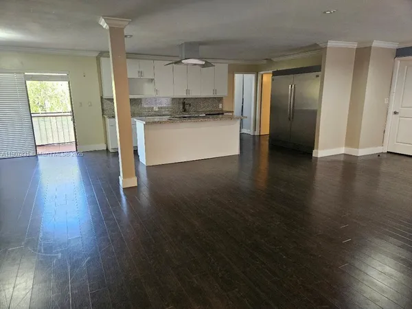 a view of a kitchen with a fridge and wooden floor