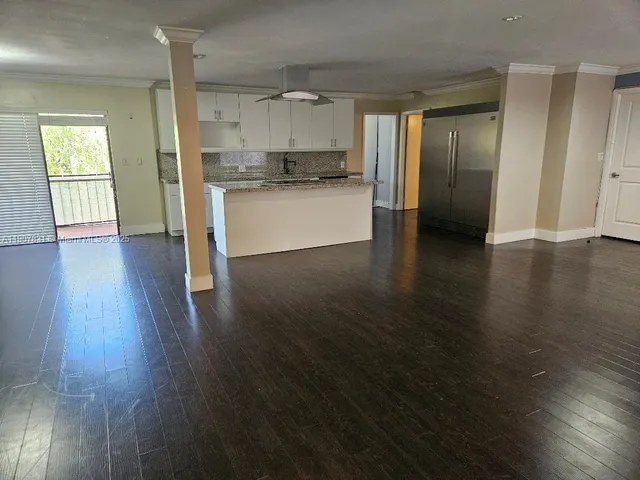 a view of a kitchen with a fridge and wooden floor
