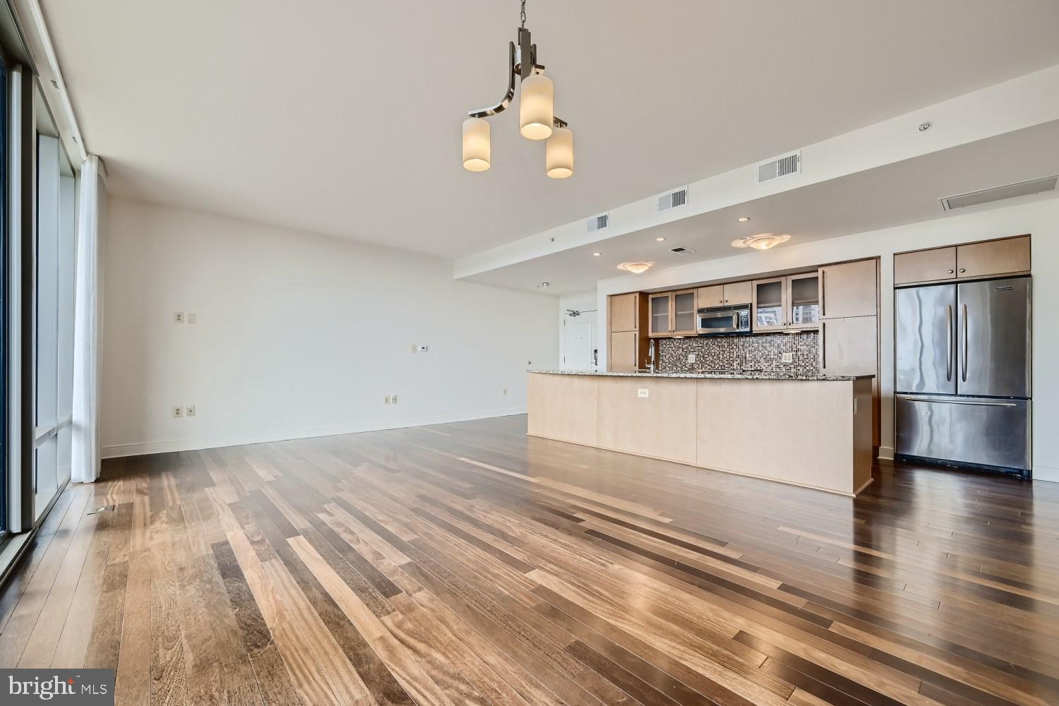 675 President Street, Unit 1709 Baltimore, MD 21202 - Photo 2 of 33 a large white kitchen with a white kitchen island a sink dishwasher and a refrigerator with wooden floor