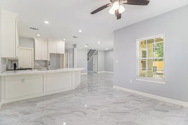 a large white kitchen with kitchen island a sink a stove a chimney a refrigerator and cabinets