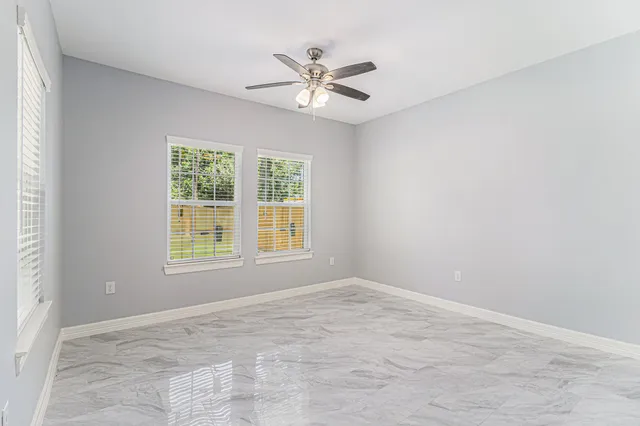 an empty room with window and ceiling fan