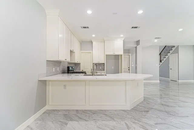 a large white kitchen with kitchen island a sink a center island stainless steel appliances and a cabinets