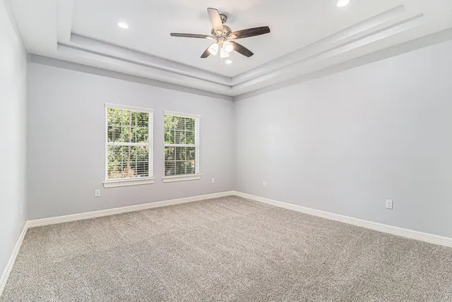 en empty room with windows and ceiling fan