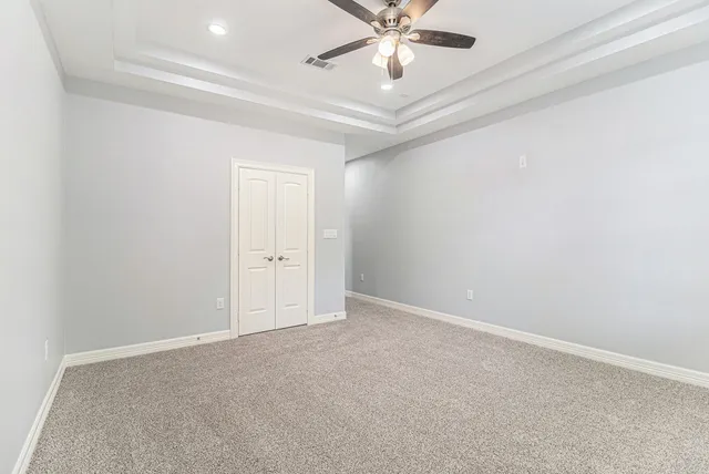 an empty room with a chandelier fan and glass door