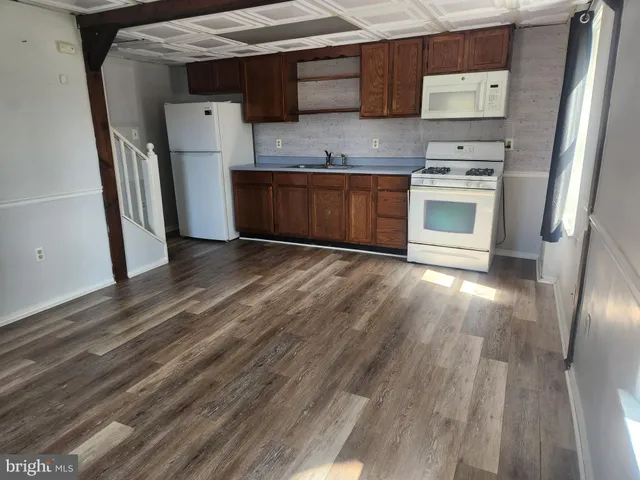 an empty room with wooden floor and stainless steel appliances