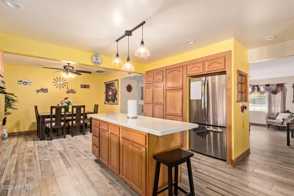 a very nice looking kitchen with a dining table chairs wooden floor and a ceiling fan