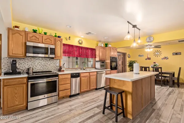 a kitchen with stainless steel appliances a stove top oven a sink dishwasher and white cabinets with wooden floor
