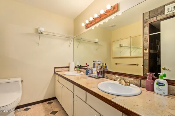 a bathroom with a granite countertop sink a toilet and a mirror