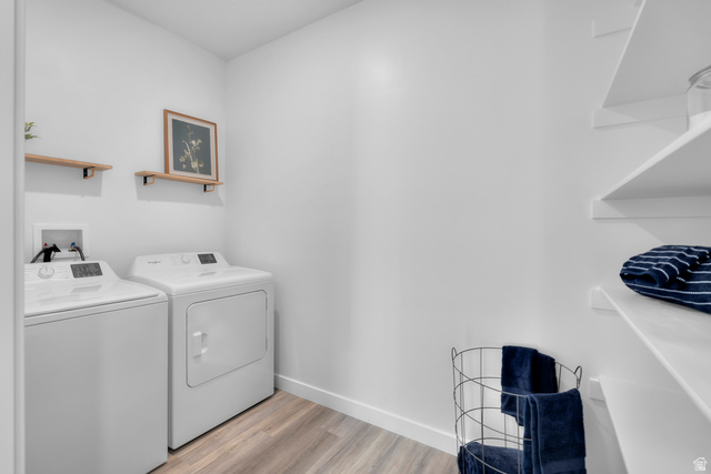 1589 South Fins Road, Unit 4178 Washington, UT 84780 - Photo 21 of 30 Dedicated laundry area featuring a washer and dryer, wood-finish flooring, white walls, two wall-mounted wood shelves, and built-in white shelving