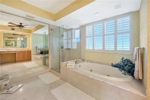 a spacious bathroom with a tub shower and a mirror