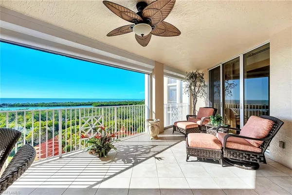 a living room with furniture floor to ceiling window and a ceiling fan
