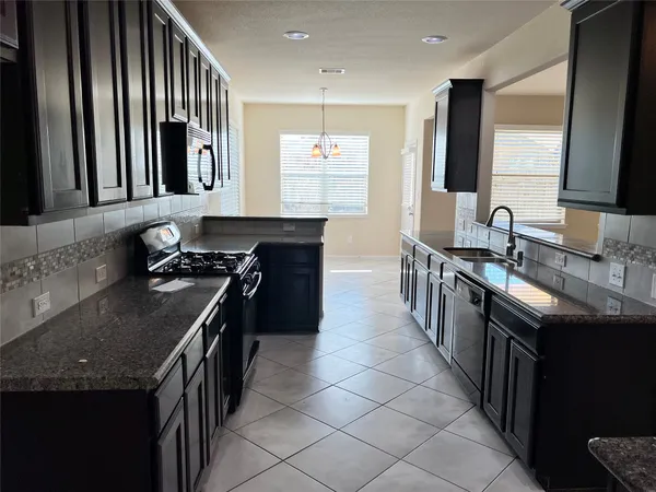 a kitchen with kitchen island granite countertop a sink stove and cabinets