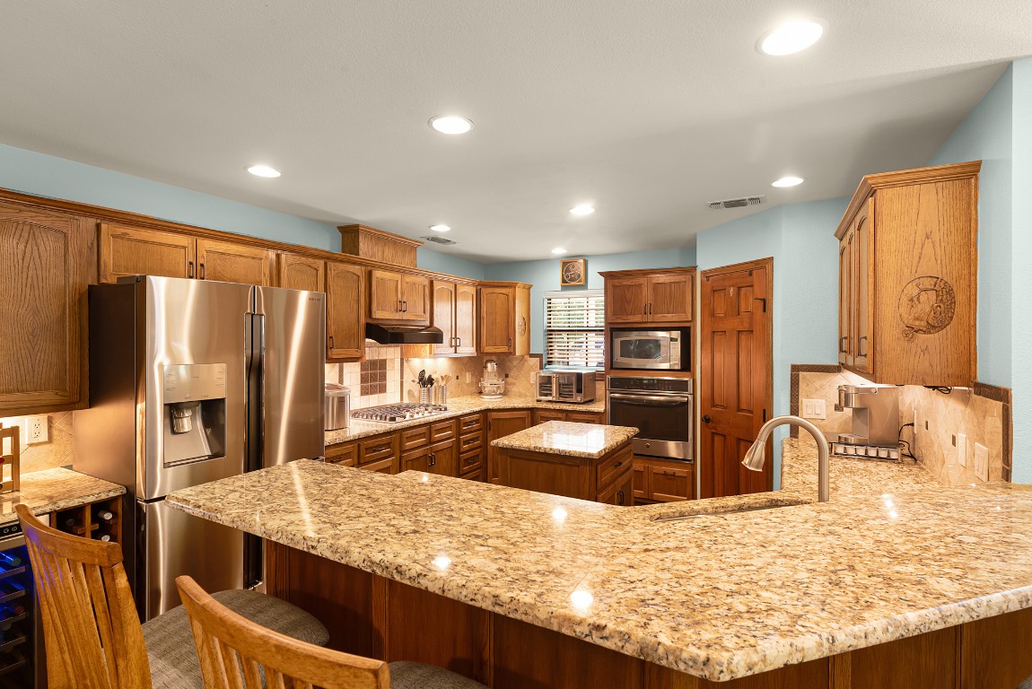 1546 Cox Road Blanco, TX 78606 - Photo 12 of 40 a kitchen with stainless steel appliances granite countertop a sink refrigerator and microwave