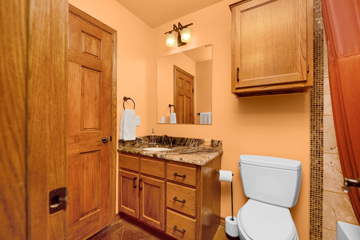 1546 Cox Road Blanco, TX 78606 - Photo 15 of 40 a bathroom with a granite countertop toilet sink and mirror