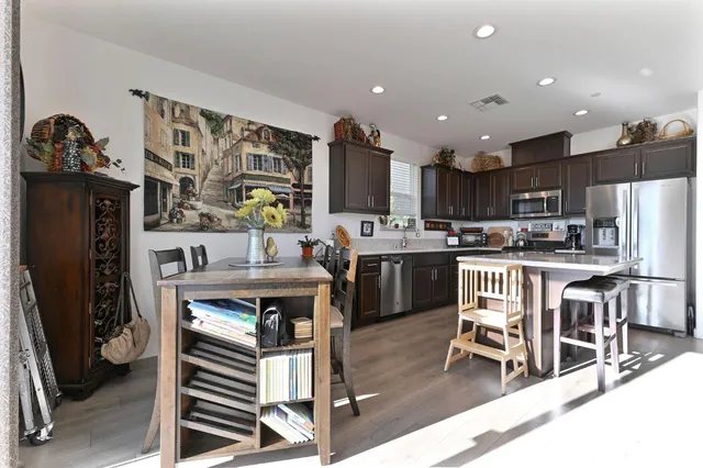 a kitchen with stainless steel appliances granite countertop a refrigerator a sink dishwasher a stove and white cabinets with wooden floor