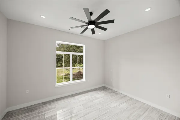 a view of empty room with wooden floor and fan