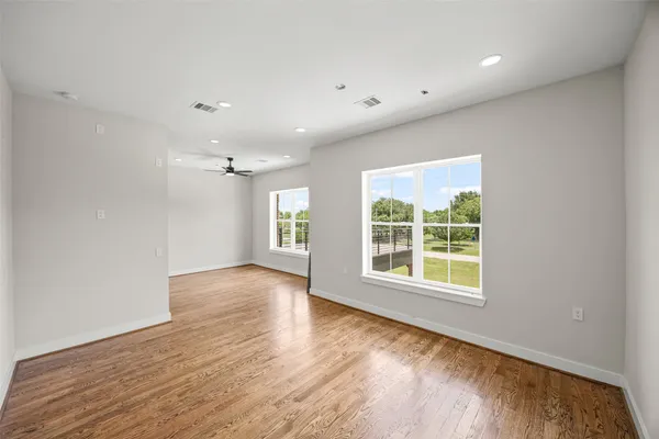 an empty room with wooden floor and windows