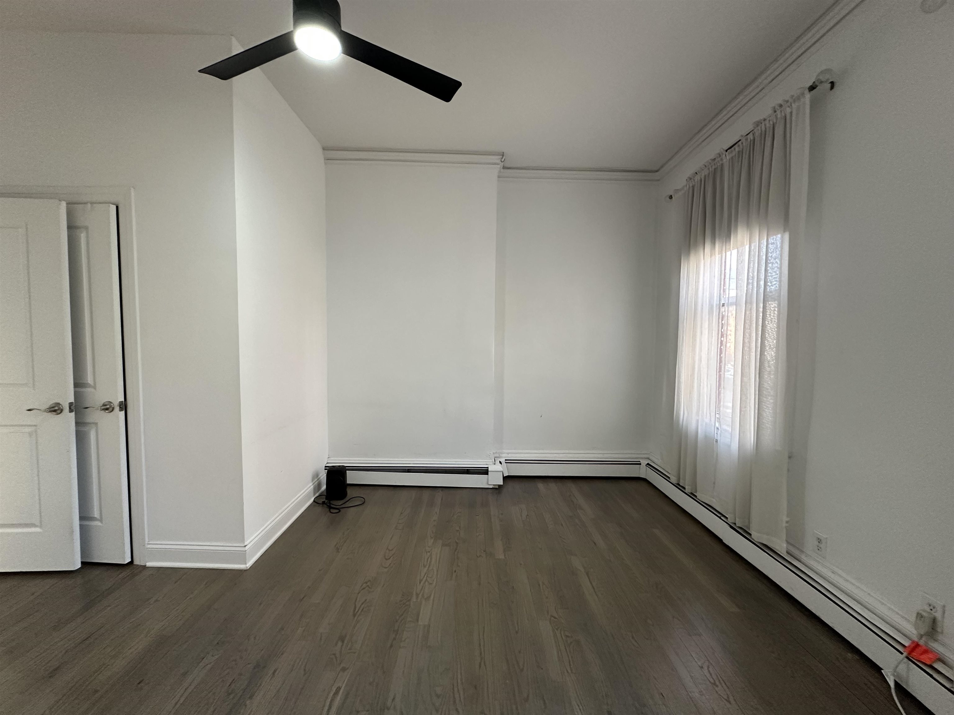 297 4th Street, Unit 2 Jersey City, NJ 07302 - Photo 17 of 19 an empty room with wooden floor fan and windows