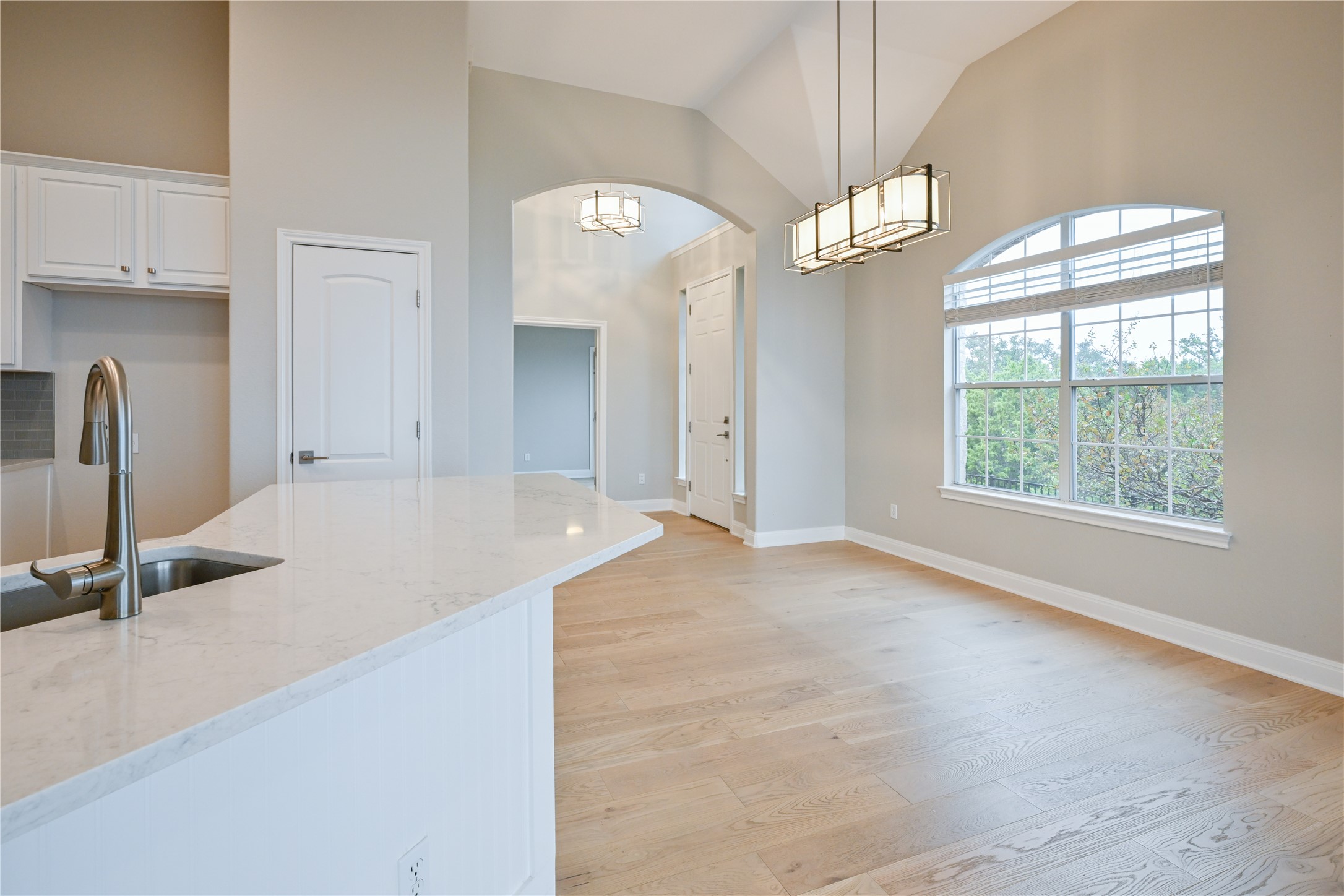 232 Sunrise Ridge Loop Austin, TX 78738 - Photo 12 of 37 Open concept living space featuring vaulted ceilings, wood-finish flooring, and a large arched window