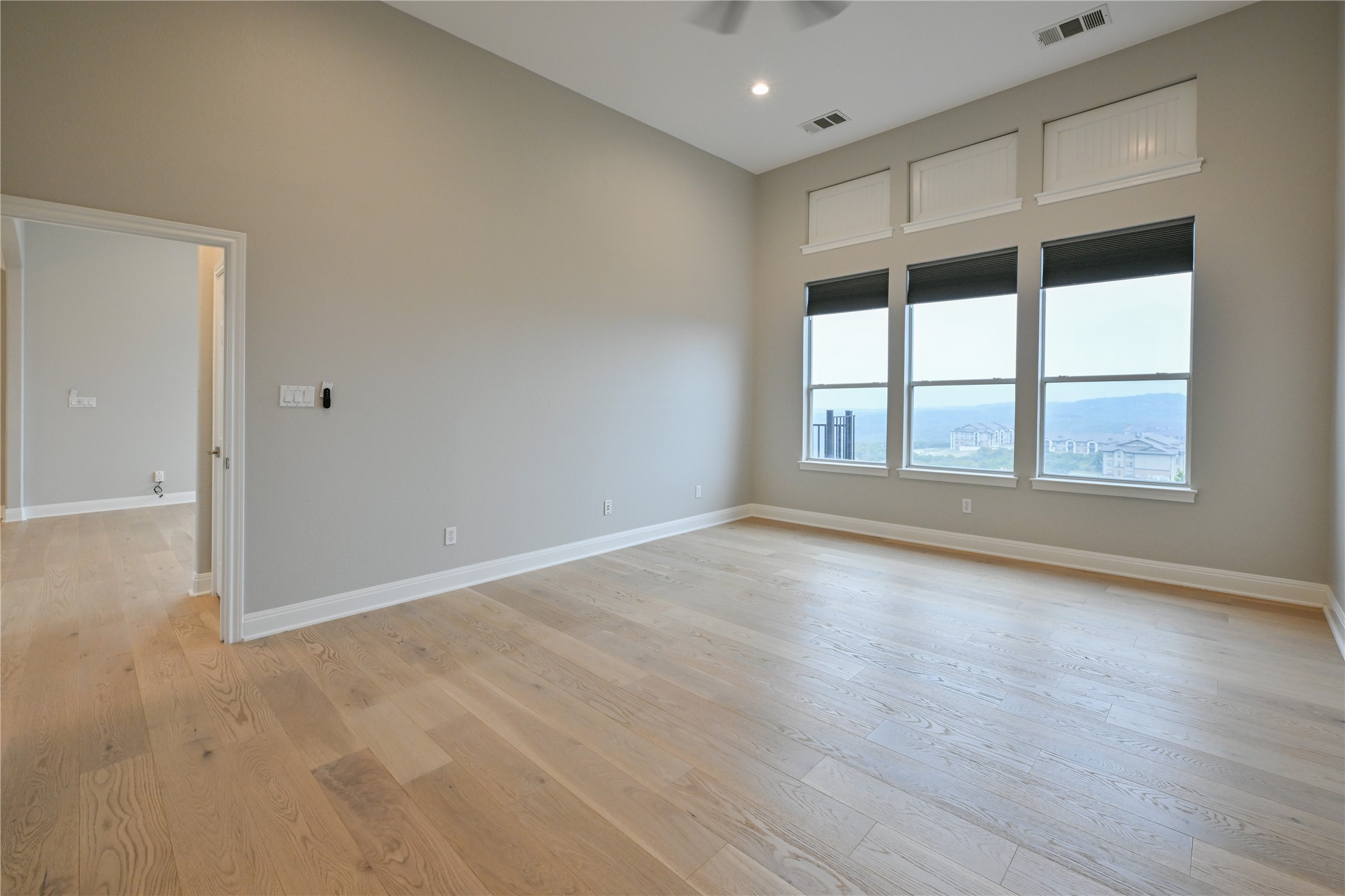 232 Sunrise Ridge Loop Austin, TX 78738 - Photo 17 of 37 Spacious room featuring light wood-finish flooring, high vaulted ceilings, and a wall of three large windows with roller shades