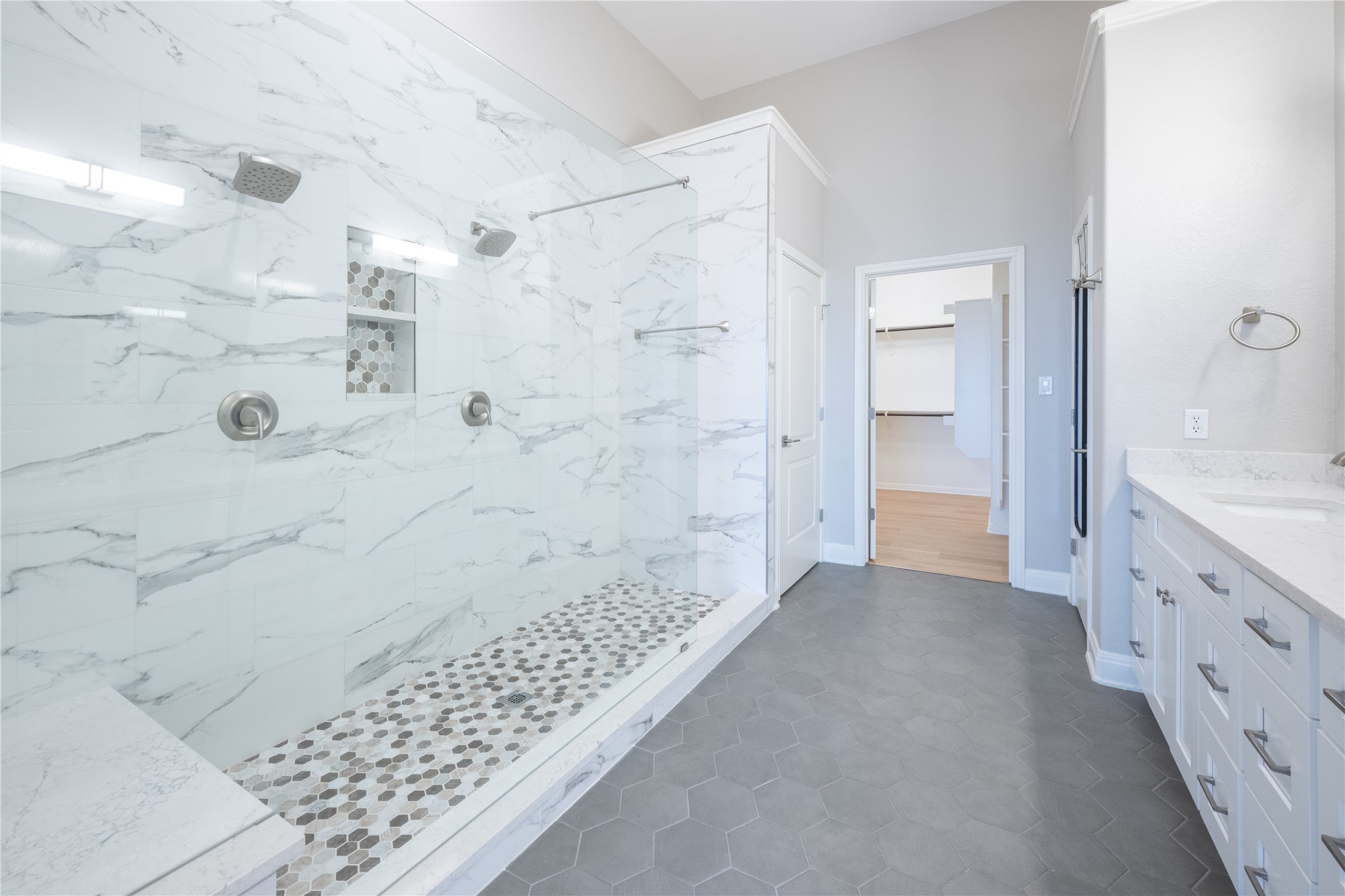 232 Sunrise Ridge Loop Austin, TX 78738 - Photo 20 of 37 Spacious bathroom with a walk-in shower featuring dual showerheads, a built-in bench, and marble-look wall tiling
