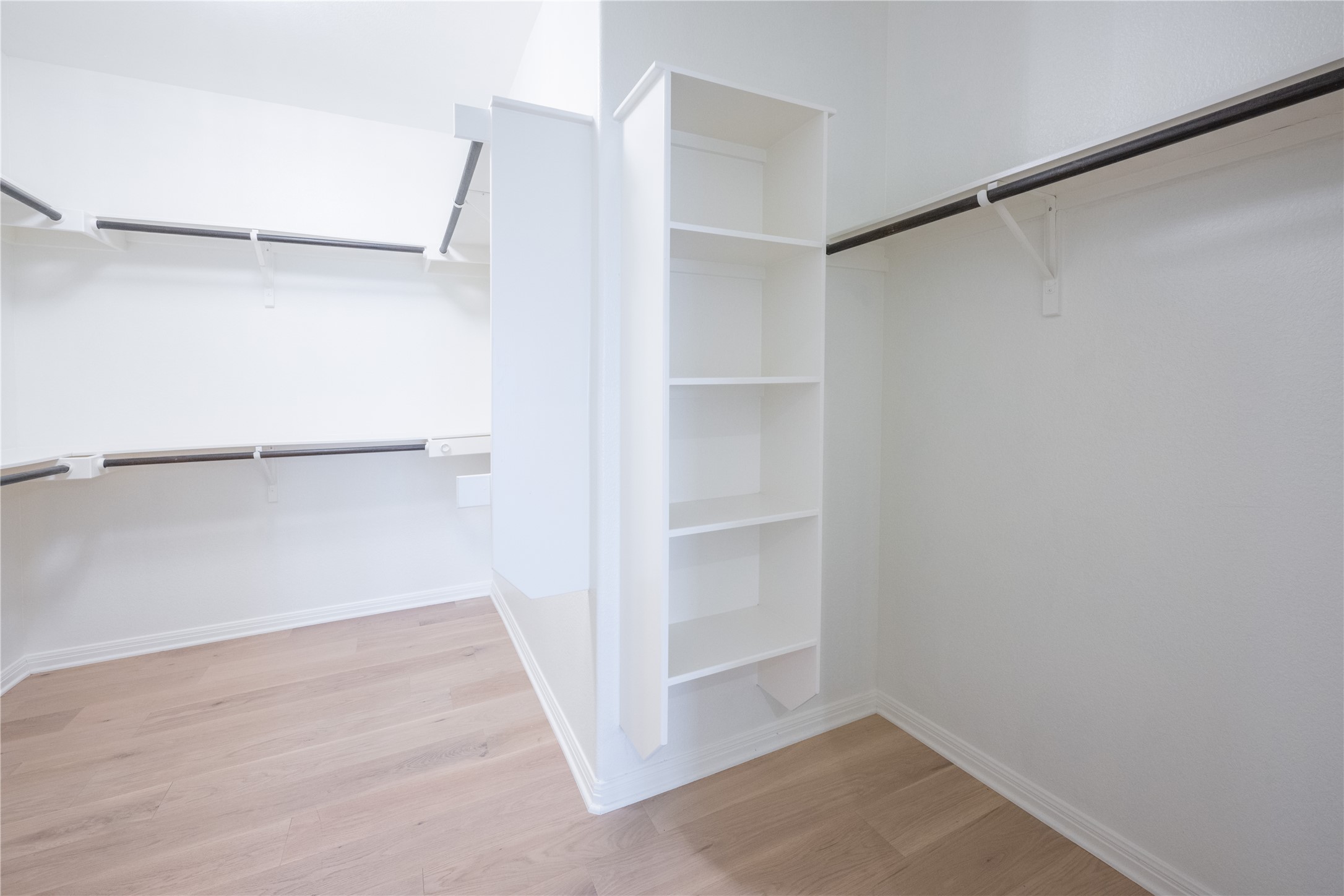 232 Sunrise Ridge Loop Austin, TX 78738 - Photo 21 of 37 Walk-in closet featuring light wood-finish flooring, white walls, built-in shelving, and multiple hanging rods