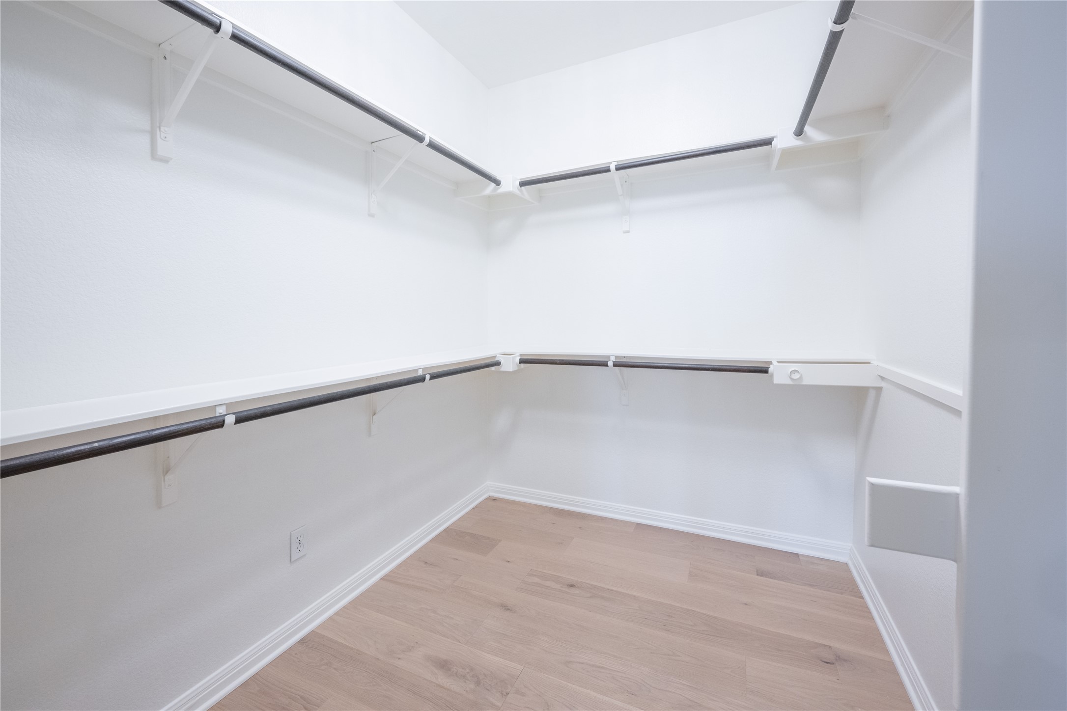 232 Sunrise Ridge Loop Austin, TX 78738 - Photo 22 of 37 Walk-in closet featuring light wood-finish flooring, white baseboards, white walls, built-in shelving, and metal hanging rods