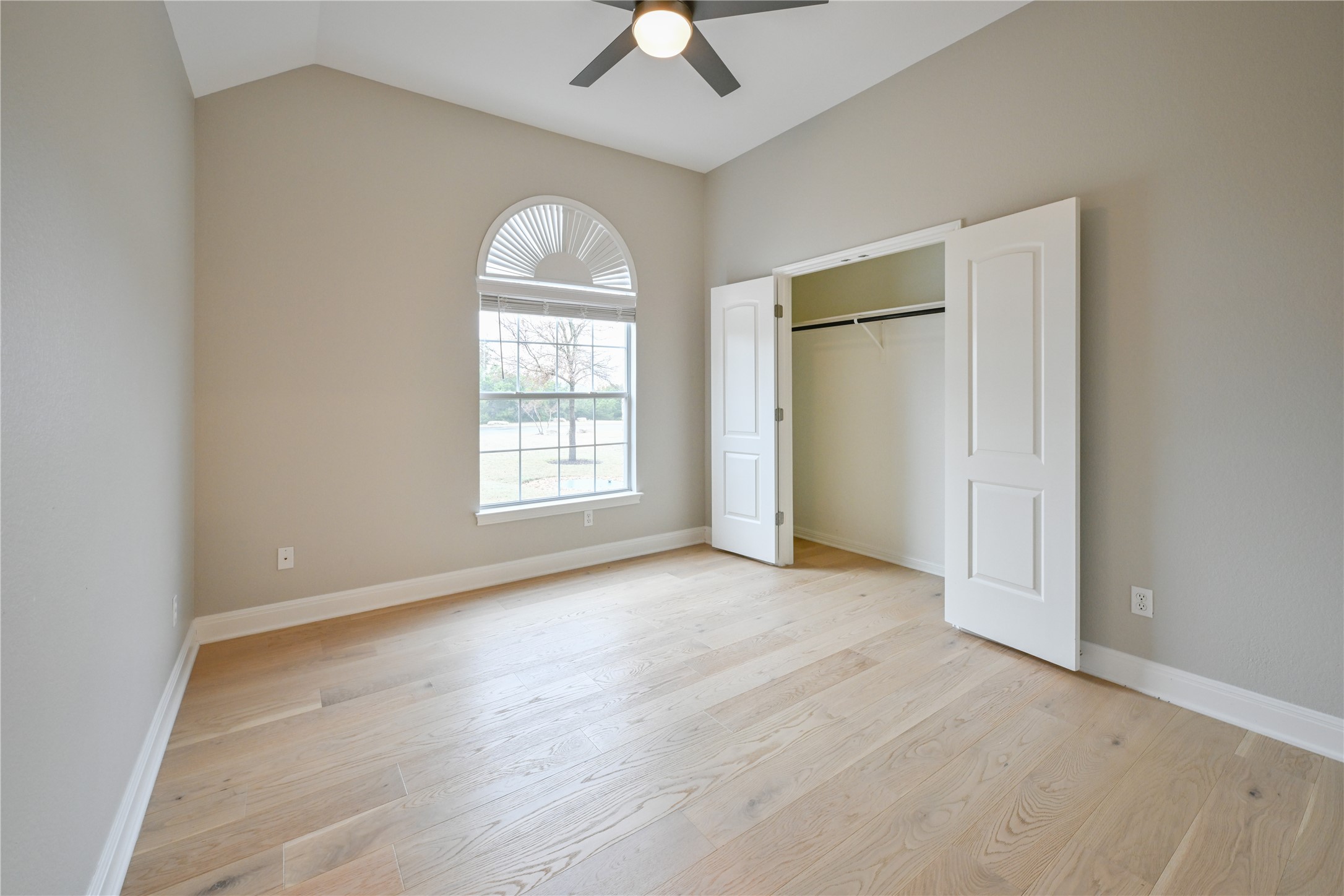 232 Sunrise Ridge Loop Austin, TX 78738 - Photo 24 of 37 Spacious room featuring vaulted ceilings, light wood-finish flooring, and a large arched window with grid detailing