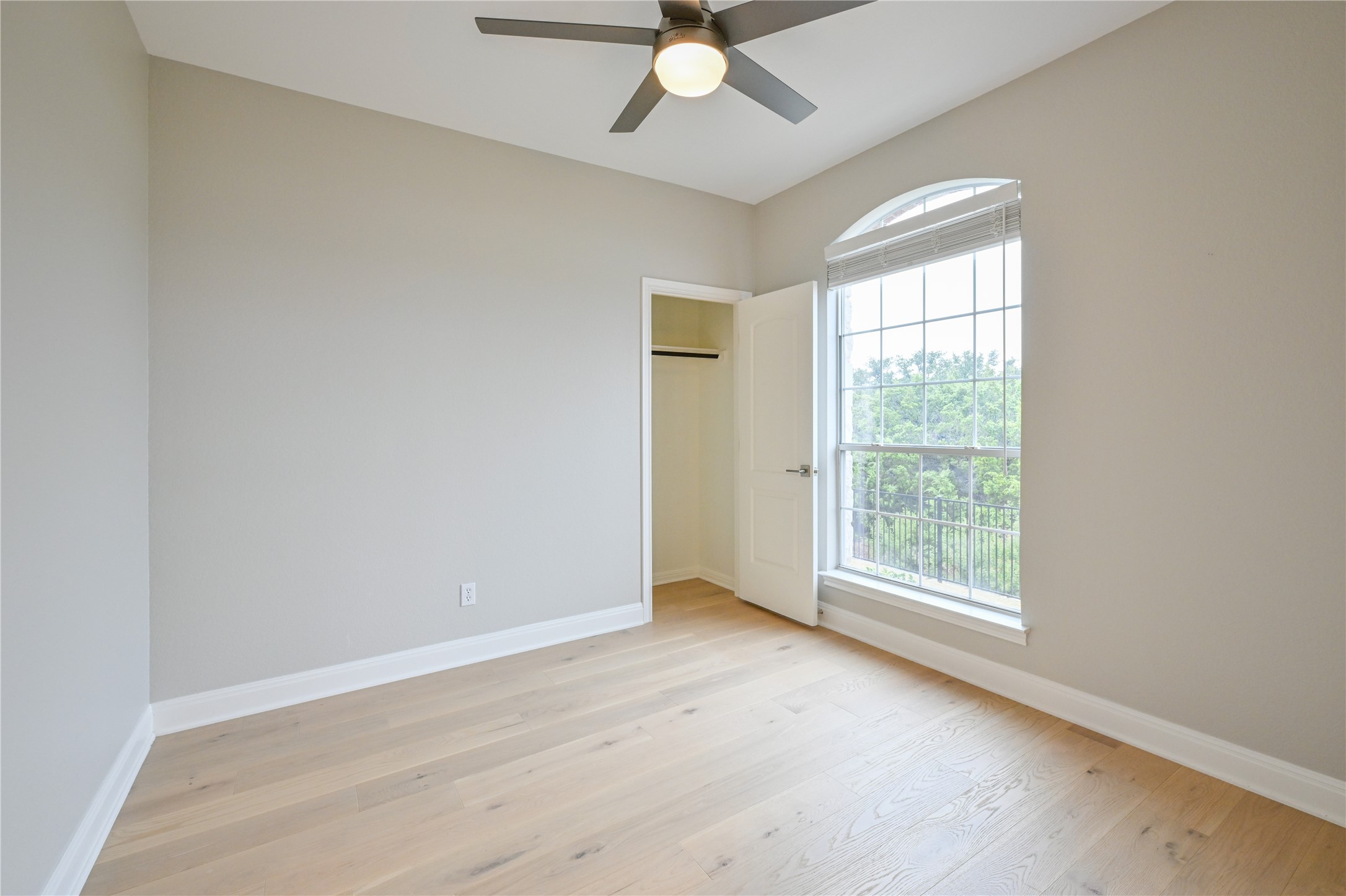 232 Sunrise Ridge Loop Austin, TX 78738 - Photo 26 of 37 Room featuring wood-finish flooring, a contemporary ceiling fan with integrated lighting, and an arched window with grid panes