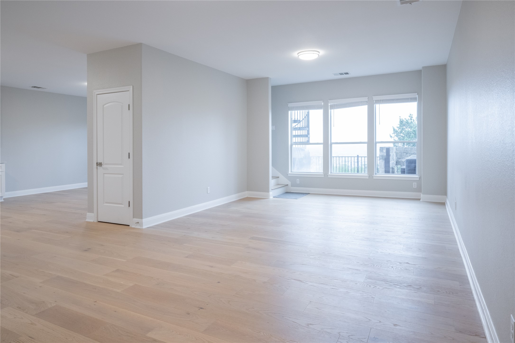 232 Sunrise Ridge Loop Austin, TX 78738 - Photo 30 of 37 Spacious interior featuring light wood-finish flooring throughout, a three-panel window ensemble, a built-in overhead light fixture, and light gray wall finishes with white trim