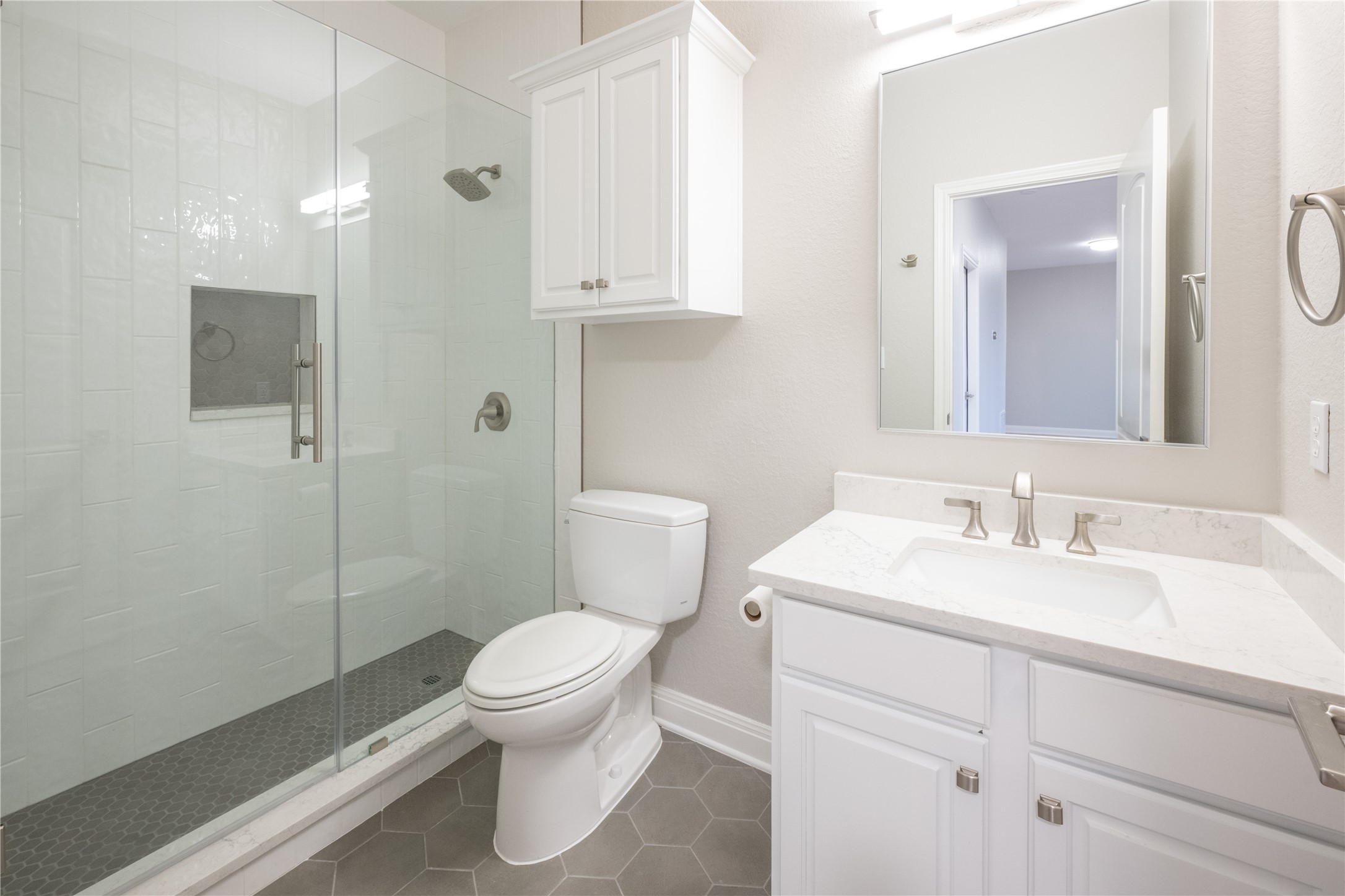 232 Sunrise Ridge Loop Austin, TX 78738 - Photo 33 of 37 Bathroom featuring a glass-enclosed shower with white subway tile and hexagonal floor tile, a white vanity with a light-colored countertop, and a large wall mirror