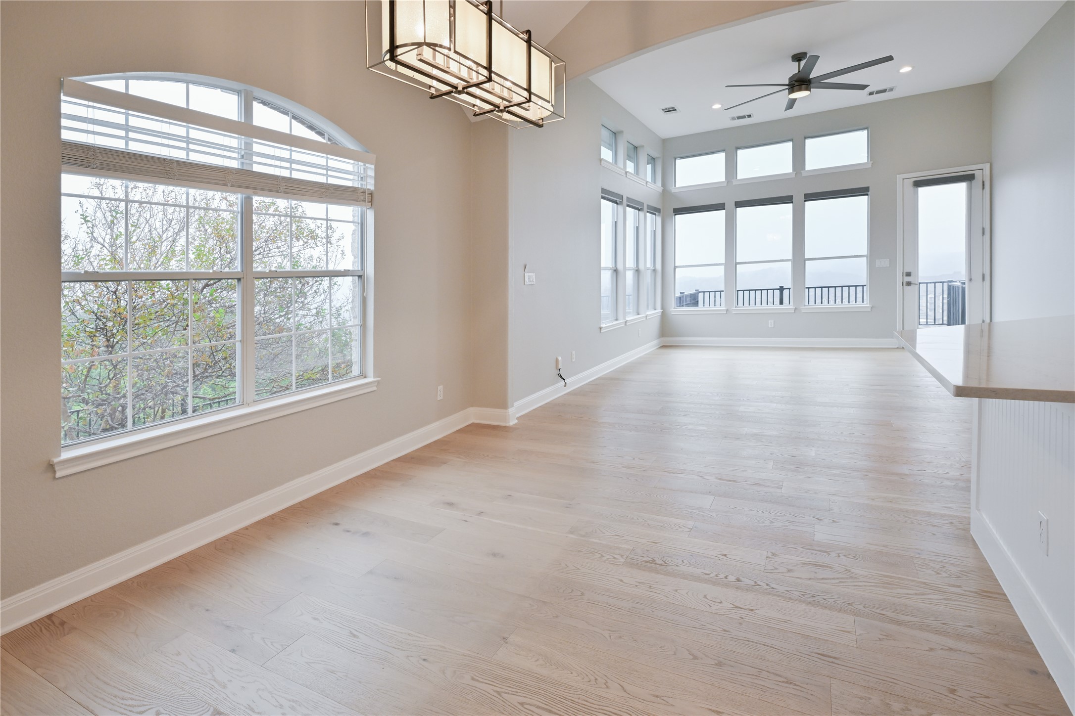 232 Sunrise Ridge Loop Austin, TX 78738 - Photo 6 of 37 Spacious open-concept room featuring light wood-finish flooring, high vaulted ceilings, and extensive window arrays