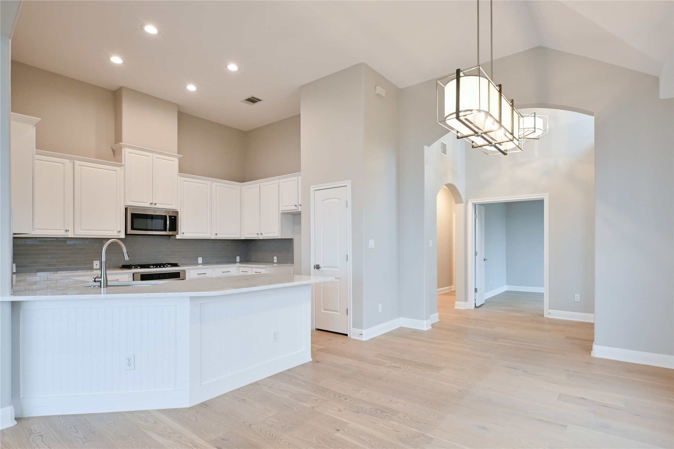 232 Sunrise Ridge Loop Austin, TX 78738 - Photo 8 of 37 Open-concept kitchen and living area featuring light wood-finish flooring, white cabinetry, a large kitchen island with beadboard paneling, and stainless steel appliances