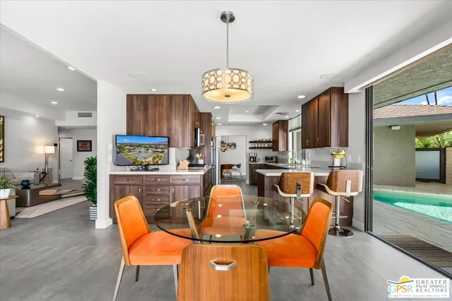 a view of a dining room with furniture a chandelier and large window