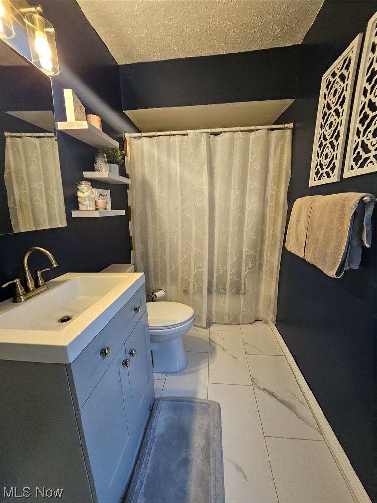19714 Drake Road Strongsville, OH 44149 - Photo 16 of 32 Bathroom with tile flooring, a textured ceiling, toilet, and vanity with extensive cabinet space