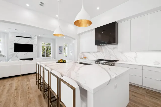 a large kitchen with stainless steel appliances kitchen island granite countertop a large counter top and a wooden floors