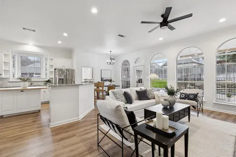 a living room with lots of white furniture and view of kitchen