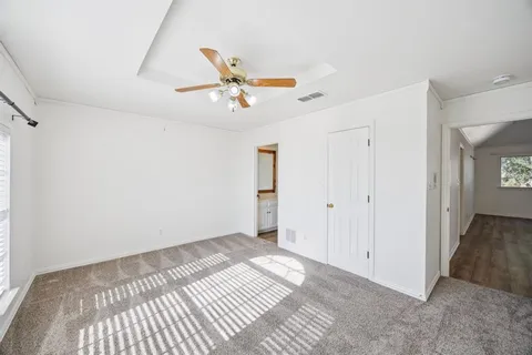 an empty room with windows and fan